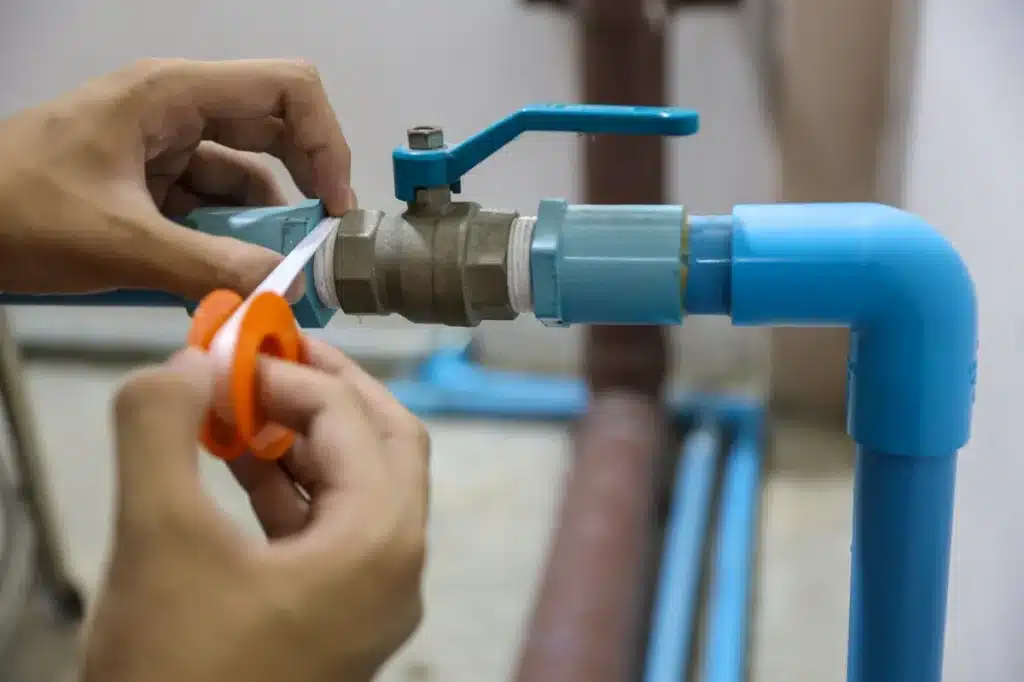 Réparation d'une fuite d'eau dans un tuyau à l'aide de ruban d'étanchéité par un technicien.